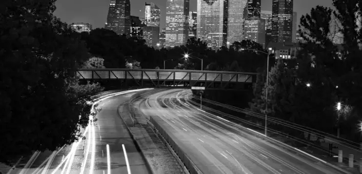 Aerial view of city of Houston showcasing buildings in the background and a highway of cars in the foreground